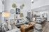 Chic open-concept living room and kitchen with stylish gray sectional, elegant wall art, and modern white cabinetry.