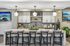 Modern kitchen with chic pendant lighting, stylish bar seating, and elegant tile backsplash. Features luxurious countertops and indoor greenery for a fresh atmosphere.