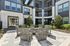 Inviting outdoor courtyard with contemporary seating around a stylish fire pit, surrounded by lush greenery and a modern apartment building backdrop.