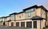 Contemporary two-story townhouses with sleek design, private garages, and chic exteriors under a clear sky.