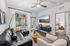 Inviting living room with modern black leather sofa, textured armchair, and stylish decor overlooking a sunny window view.