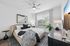 Modern bedroom with elegant design featuring plush bed, stylish decor, and large window allowing natural light. Cozy atmosphere with artistic accents and sleek furnishings.