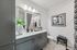 Contemporary bathroom with sleek gray cabinetry, elegant fixtures, and modern decor featuring stylish wall art and a plush patterned shower curtain.