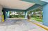 Inviting covered parking area with electric vehicle charging station, surrounded by lush greenery and modern apartment buildings.