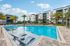 Luxurious apartment complex with a sparkling swimming pool, surrounded by palm trees and modern architecture, perfect for relaxation and leisure.
