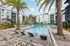 Luxurious apartment complex with a stunning resort-style swimming pool surrounded by palm trees and modern sun loungers.