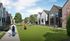 Charming suburban neighborhood with modern townhouses, lush green space, and a welcoming path ideal for families and outdoor activities.