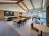 Spacious modern communal area with vaulted ceilings, stylish wooden accents, a sleek kitchen with bar seating, and a cozy seating arrangement perfect for gatherings.