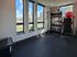 Bright and modern fitness room with large windows, equipped with weight rack and exercise equipment.