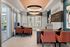 Elegant office space with modern design, featuring stylish orange armchairs, large windows, and contemporary lighting.
