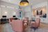 Modern lounge area with plush pink seating, sleek workstations, and a chic coffee station, accentuated by elegant lighting fixtures.