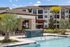 Inviting outdoor pool area with modern cabanas and lush palm trees, set against a stylish apartment complex.