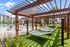 Luxurious outdoor leisure area with hammocks beneath a stylish pergola, adjacent to a sparkling swimming pool and modern apartment buildings.