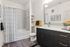 Modern bathroom featuring elegant gray tiled shower, sleek vanity with black cabinetry, and stylish decor accents including black and yellow towels.