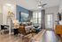 Chic living room with modern decor, cozy seating, and natural light streaming through large windows; features an elegant blue accent wall and contemporary ceiling fan.