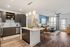 Modern open-concept kitchen and living room with sleek cabinetry, elegant lighting, and a cozy seating area with large windows.
