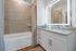 Contemporary bathroom with elegant granite countertops, a large illuminated mirror, and a modern tiled bathtub.