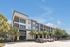Modern apartment complex with sleek architecture, large windows, and lush landscaping under a clear blue sky.