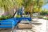 Elegant outdoor oasis featuring a vibrant blue sectional sofa, palm trees, and sleek patio design.