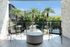 Luxurious balcony oasis with modern seating, vibrant greenery, and breathtaking palm tree views.