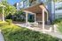 Charming outdoor patio area with modern pergola, lush greenery, and stylish seating in a vibrant apartment complex.
