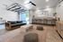 Chic modern lounge with sleek couch, cozy poufs, stylish bar seating, and vibrant accent plants, enhanced by ample natural light.