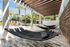 Inviting outdoor lounge with modern hammocks under a stylish pergola, surrounded by lush palm trees and resort-style pool ambiance.