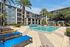 Luxurious apartment complex with a spacious outdoor pool area, surrounded by serene palm trees and modern lounging spaces.