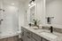 furnished bathroom with double sinks, toilet and shower