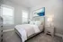 Opelika, AL Houses for Rent - Champions Square - Bedroom with Carpeted Flooring, Bed, Nightstands with Lamps, Dresser, Wall Art, and Two Windows.