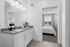 furnished bathroom with sink and mirror, peeking into bedroom with bed