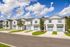 A row of modern townhouses with blue garage doors and manicured lawns under a bright blue sky