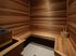 Elegant wooden sauna room with bright lighting and seating, featuring a bucket and ladle.