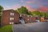 Beautiful brick apartment complex with lush greenery and a vibrant sunset sky.