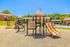 Colorful playground with slides and climbing structures amidst apartment buildings and green spaces.