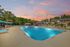 Sparkling outdoor pool surrounded by lush greenery and modern apartments at sunset.