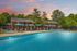 Inviting outdoor pool area with lounge chairs and umbrellas set against a picturesque sunset and lush greenery.