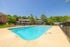 Inviting outdoor pool with lounge chairs and umbrellas in a serene apartment complex setting.