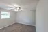 Inviting bedroom with soft carpeting, a ceiling fan, and a large window for natural light.
