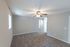 Bright living room with a ceiling fan and plush carpeting, showcasing modern neutral tones.