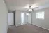 Inviting bedroom with soft carpet flooring, ceiling fan, and ample natural light from a large window.