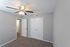 Bright bedroom with plush carpet, modern ceiling fan, and double closet doors.