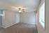 Inviting living room with a ceiling fan, plush carpet, and ample natural light.