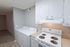Modern kitchen with white cabinets and an integrated laundry area featuring a washer and dryer.