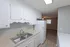 Modern kitchen with sleek white cabinets, stainless steel sink, and spacious countertop overlooking a cozy living area.