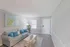 Bright living room with a comfortable gray sofa, blue cushions, modern artwork, and a wooden coffee table.