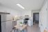 Bright and airy kitchen with sleek white cabinets, stainless steel appliances, and a cozy dining area.