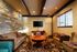 Warm and inviting living room featuring a rustic stone accent wall, elegant wooden table with chairs, and a plush patterned sofa.