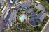 Aerial view of a luxury apartment complex with a central swimming pool and surrounding well-maintained gardens.