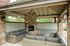 Charming covered outdoor lounge with stone fireplace, stylish seating, and natural surroundings.